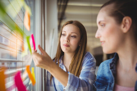 Businesswoman sticking adhesive notes window office (1)